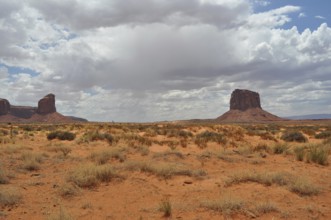 Wide dry plain with isolated rocks under dramatic skies, Monument Valley, Navajo Tribal Park,