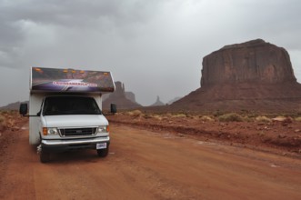 An RV on a road in Monument Valley surrounded by impressive rocks after a severe thunderstorm,