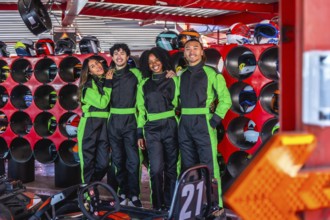 Diverse group of young adult friends smiling and posing in go kart racing suits, ready for an