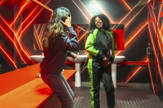 Two friendsone in a racing jumpsuit, the other casuallaugh and bond under vivid red neon in a