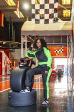 Young african american woman posing confidently in a neon green and black racing suit and helmet,