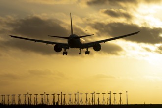 Boeing 777 commercial passenger jet aircraft in flight on approach to land over runway lights