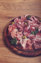 Assortment, sliced meat appetizer, prosciutto, salami and ham, with olives, on a wooden board,