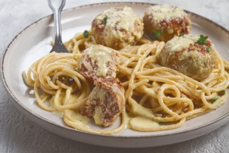Spaghetti with chicken meatballs, with cream sauce, and parmesan cheese, and decorated with
