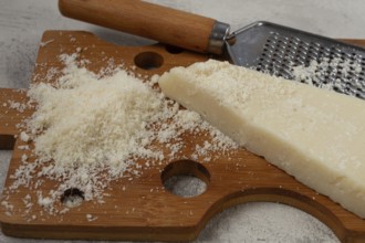 Freshly sliced and grated cheese, parmesan cheese, Gran gusto. Grana padano. on a wooden chopping