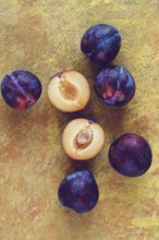 Plums scattered on the table, fresh, top view, yellow-orange background, no people