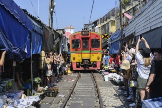 Mae Klong, Thailand. March 15th 2025. Tourists crowd around the arriving 14.30 train as it passes