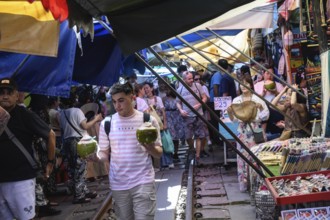 Mae Klong, Thailand. March 15th 2025. Tourists shop for fresh coconut juice at the Mae Klong