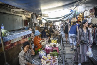 Mae Klong, Thailand. March 15th 2025. Tourists wander along the train rail lines with Thai market