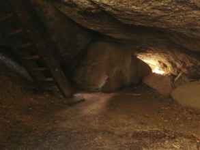 Interior view of a rocky cave, Girgel cave with wooden stairs and light at the end, Franconian