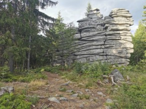 Large rock formations surrounded by trees and vegetation in a forest, Franconian mountain trail,