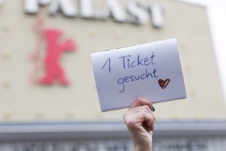 A visitor holds up a note with the inscription 1 ticket wanted for the film Everything Everywhere
