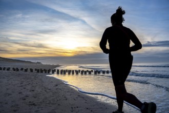 Winter on the North Sea, sunset at the beach, joggers, beach walkers, coastal protection, through
