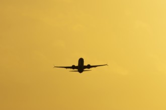 Airbus commercial passenger airliner jet aircraft taking off in flight silhouette at sunset at