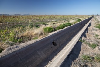 Buckeye, Arizona - A an empty concrete irrigation ditch runs next to an unused field on a farm in