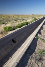 Buckeye, Arizona - A an empty concrete irrigation ditch runs next to an unused field on a farm in