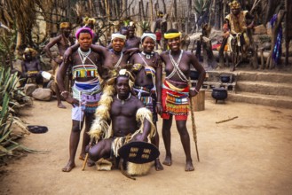 Group of Zulu people dressed in traditional attire, performing at an outdoor cultural event likely