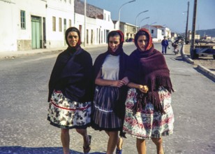 Three young women teenage girls wearing traditional clothes dressed in shawls and headscarfs,