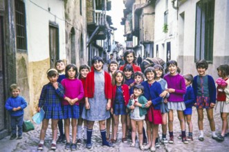 Group of children posing for photograph standing across a historic cobbled street, Portugal, Europe