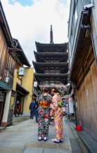 Two Japanese woman in kimonos in an alley, at the back five-story Yasaka Pagoda of the Buddhist