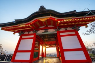 Sunset over the city with sun stars, view through the red Nishimon Gate, Kiyomizu-dera Temple, in