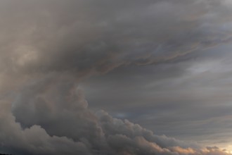 Clouds form in the sky. It is late in the day. The clouds are thick and grey. The sky shows various