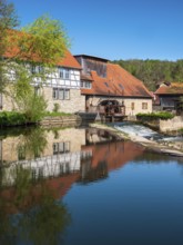 The historic water mill is reflected in the river Ilm, Buchfart, Weimarer Land, Thuringia, Germany