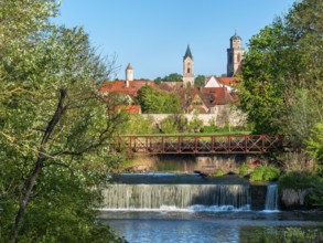 View over the Wörnitz river with weir to the historic old town with city wall and St. Georg