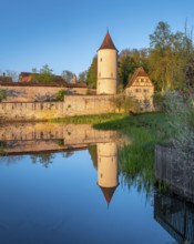 Digestive tower with park guard house on the city wall in morning light, reflection in the