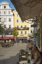 Regensburg, Germany. October 7th 2024 A woman sits at a café in the square of the medieval UNESCO