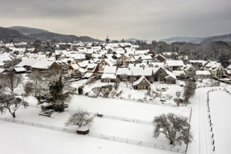 Snowy village with half-timbered houses and gardens under a grey sky, Herleshausen in northern