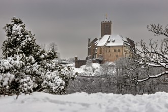 Medieval castle in winter with snow-covered landscape and cloudy sky, The Wartburg near Eisenach in