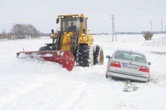 Car stuck in snow gets help from a loader to get free in Skurup municipality, Skåne county, Sweden,