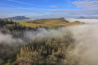 Foggy landscape in Hegau with hills and forests under a clear blue sky, Hohenkrähen castle ruins,