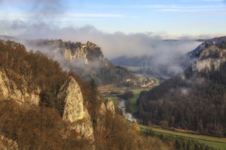 Foggy rock formations and autumn forest in the valley, the Danube snakes through, castle on a rock,