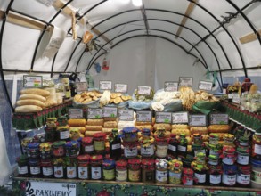 Colourful market stand with various types of jams and breads and local specialities under a tent,