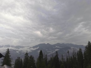 View of a mountainous landscape with clouds and conifers wrapped in fog, Zakopane, hiking in the