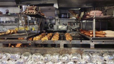 Large grill with various meats and local specialties over an open fire in a kitchen, Zakopane,