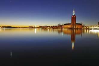A nocturnal skyline with illuminated building and reflecting lights in the water, Stadshuset, Nobel