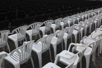 White plastic chairs standing in rows, seating at an open-air event, empty, vacant