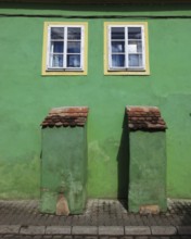 Green house façade with two small windows in the old town of Sighisoara, German Sighisoara, town in