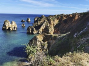 Rock formations above the clear blue sea under a wide sky, Lagos, Algarve, Portugal