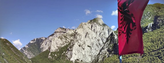 Mountain landscape with the Albanian flag against a clear sky and impressive rock formations, Peaks