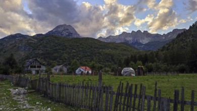 Idyllic farm against a dramatic mountain backdrop in the warm light of sunset, Peaks of the