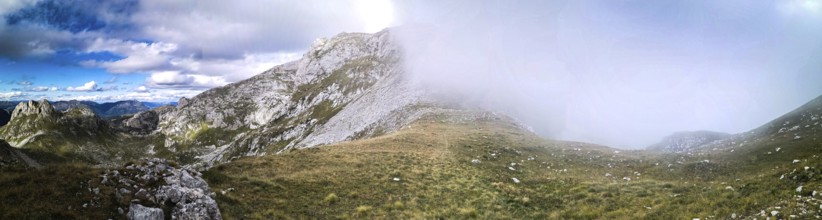 Panorama of a mountain landscape with fog moving over the hills and contrasting the sky, Peaks of