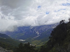 Dramatic cloud cover over a wide valley and towering mountains, Peaks of the Balkans, hiking in the