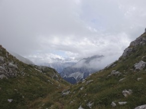 Snowy valley surrounded by mountains, partly obscured by clouds and fog, Peaks of the Balkans,
