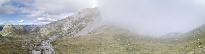 Mountain landscape with fog that partially obscures the view, under a changing sky, Peaks of the