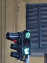 Close-up of a green traffic light in Tirana green letter T in front of a building with shutters