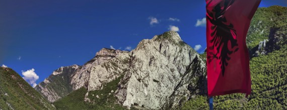 Alpine landscape with an Albanian flag and majestic mountains under blue sky, Peaks of the Balkans,